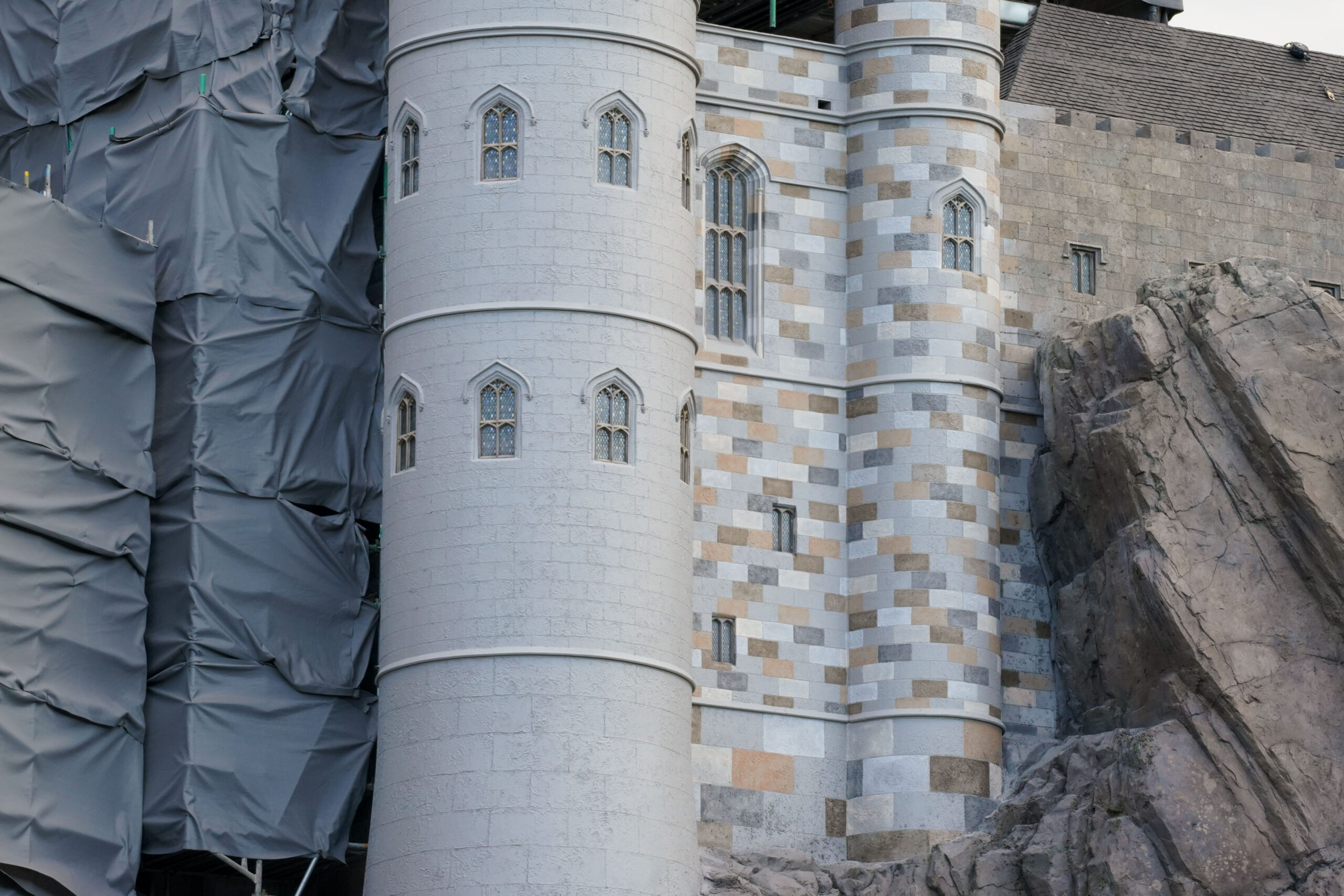 Workers perform detailed restoration work on Hogwarts Castle's exterior facade